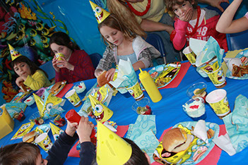 children gathered for a party decorated with sponge bob square pants. Children are having burgers for lunch.