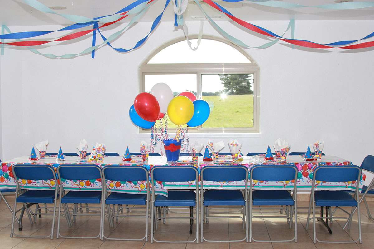 Photo showing party room setup at Emerald Dolphin with multi colored balloons and table settings.