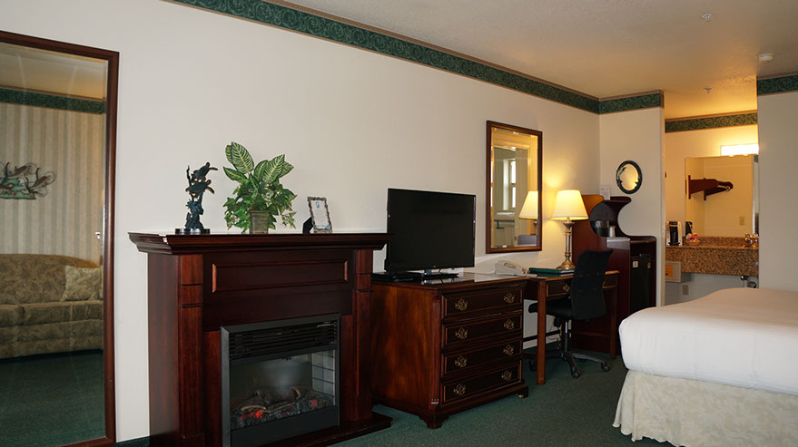 European King Size Bed Photo depicts King Bed, Chest of drawers, electric fireplace, TV, writing desk, microwave, mini fridg, full length mirror.