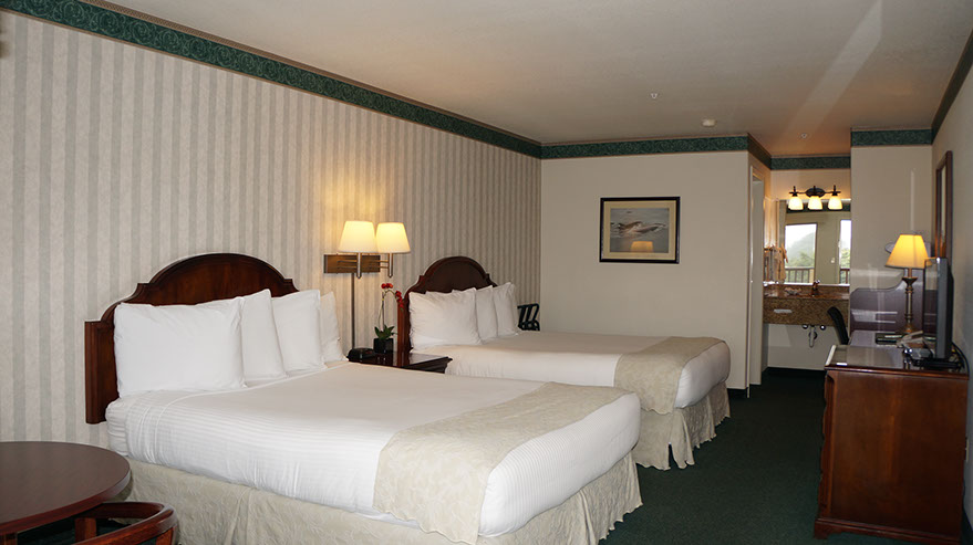 2 Queen Suite This family friendly 2 queen suite is showing 2 queen beds, dresser, writing desk, night stand with lamps and separate dressing area.