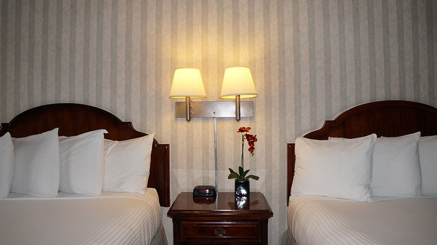 2 Queen Suite Guest Room Photo showing 2 queen beds with night stand, double lamps and an alarm clock.