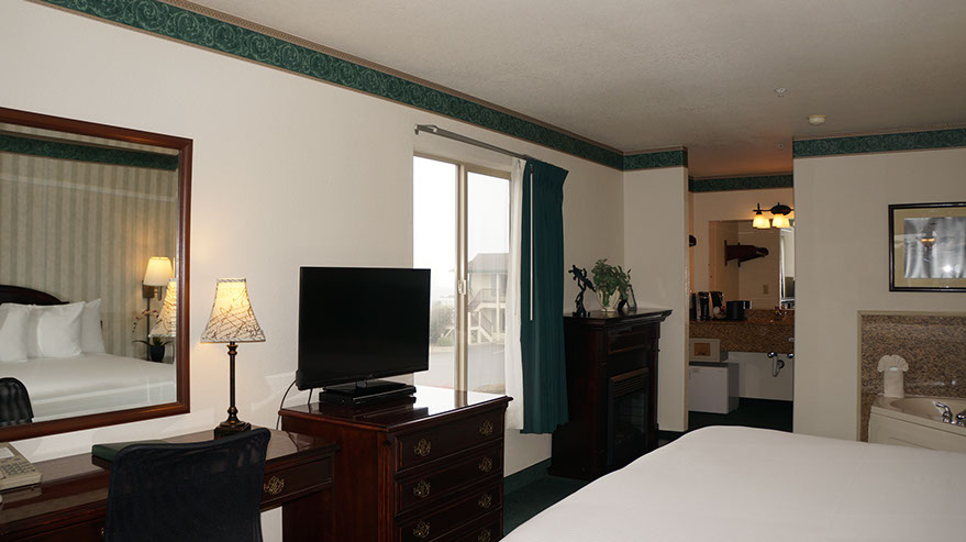 European King Size Bed European King Size Bed guest room showing photo of partial bed, jacuzzi, chest of drawers with flat screen tv, writing desk, lamp, bathroom.