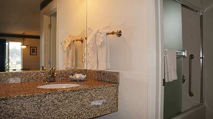 Guest sink area with large mirror, and entrance to guest bath with tub/shower that has grab bars.