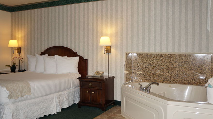 Queen Size Guest Room Photo shows a different angle with jacuzzi tub that seats 2, quen bed, night stands with lamps, direct dial phone.