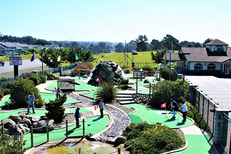 2 young children playing a round of golf at Ed's Mini Golf, located at Emerald Dolphin in Fort Bragg CA