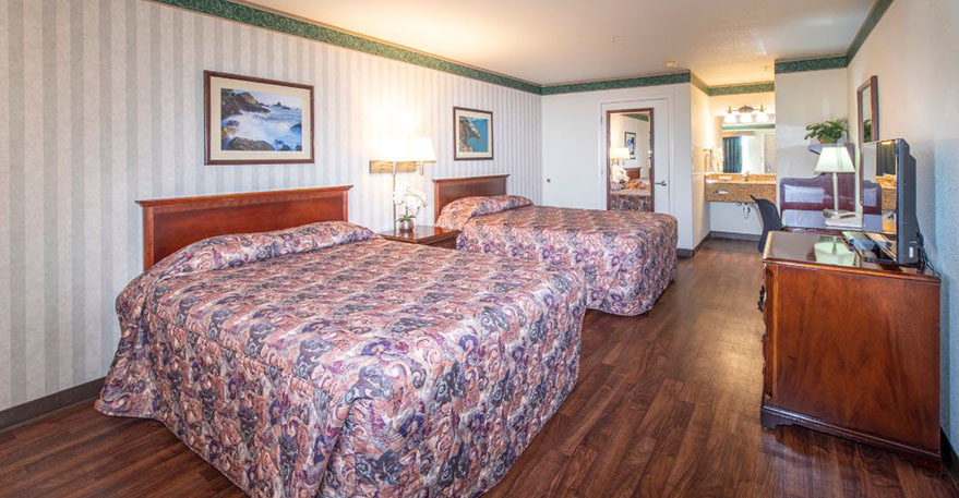 2 Queen Suite Guest Room Photo showing 2 queen beds with night stand, double lamps and an alarm clock.